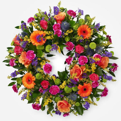 Celebration Wreath - A vibrant open wreath bursting with rich pink, orange and purple blooms, beautifully finished with fresh greenery.